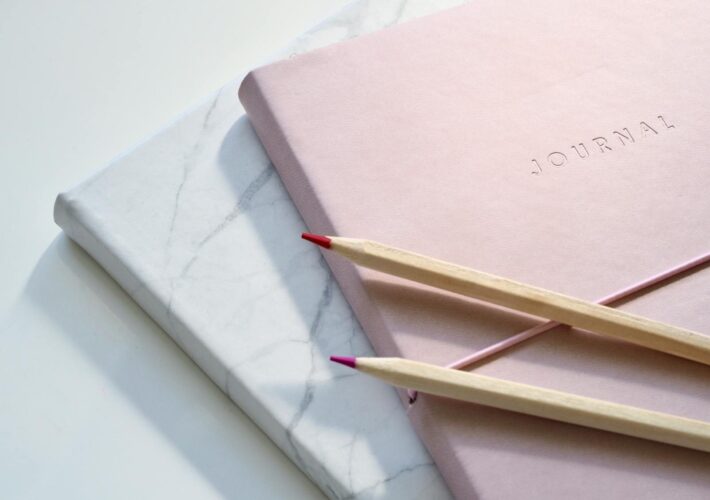 Close-up of a pink journal with pencils on a marble top. Perfect for note-taking or planning.