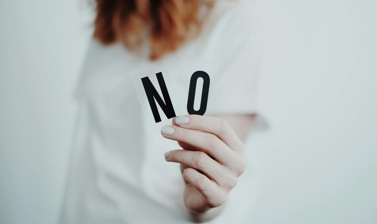 Close-up of a person holding a "No" sign, symbolizing rejection or disagreement.