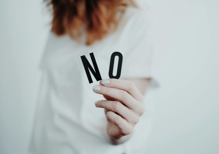 Close-up of a person holding a "No" sign, symbolizing rejection or disagreement.
