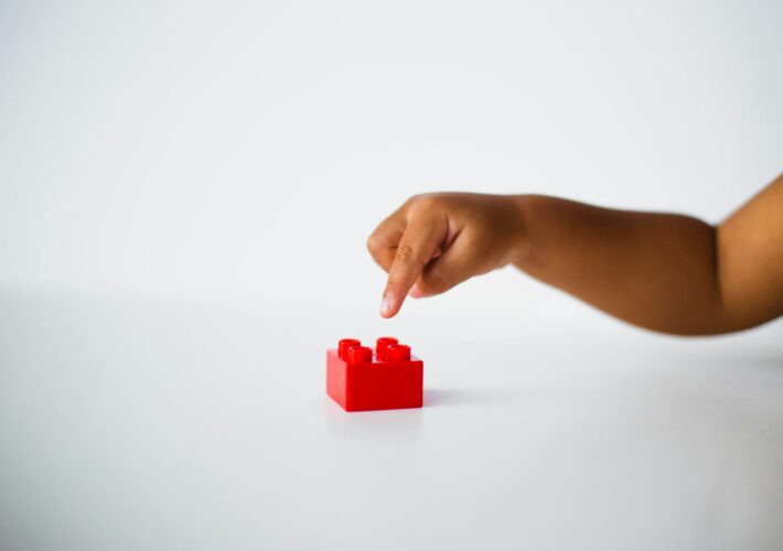 child pointing to red interlocking brick toy