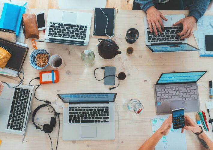 people sitting down near table with assorted laptop computers