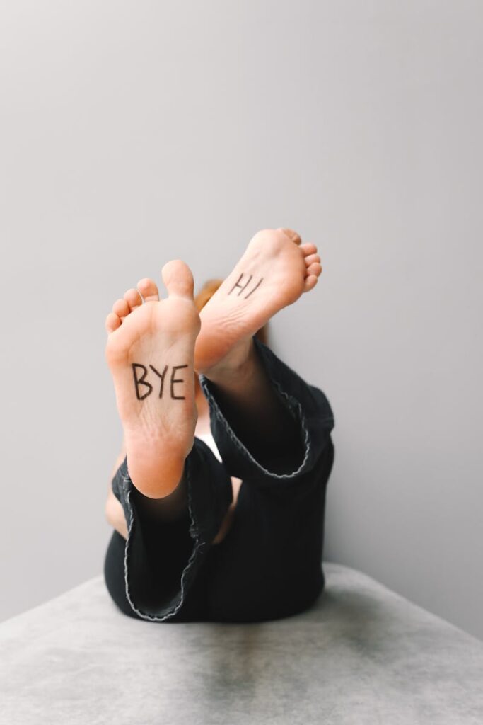 A fun shot of tilted feet with 'Hi' and 'Bye' written on the soles, indoors.