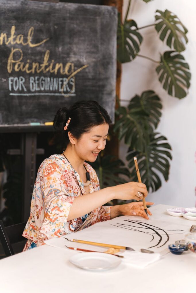 A woman in an art class practices oriental painting techniques on paper.