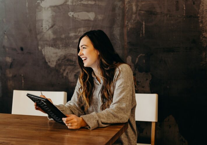 woman sitting around table holding tablet
